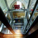 Van den Beemd maakt exclusieve glazen panorama liftschacht met RVS rotules in een oud Klooster. Luxeuze liftschacht in 5-sterren Kruisherenhotel Maastricht.